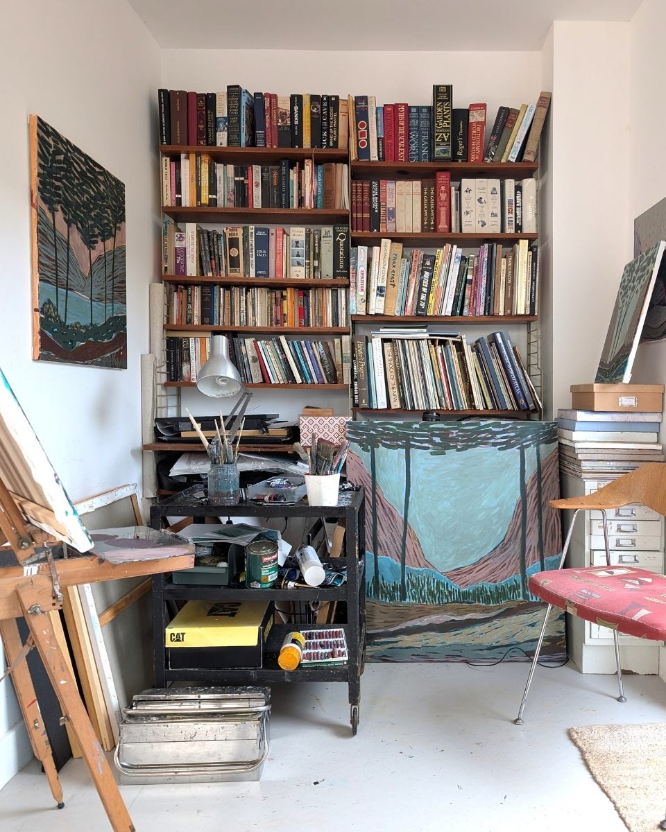 Wide-shot of Kulbir Bhandal’s studio, featuring mounted canvases amongst a library of art books and architectural tools.