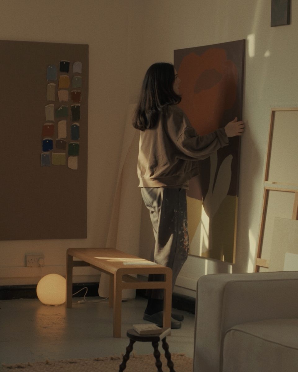 Artist Laurie Maun hanging a large-scale abstract painting on her studio wall, showcasing her signature fluid forms for Partnership Editions.