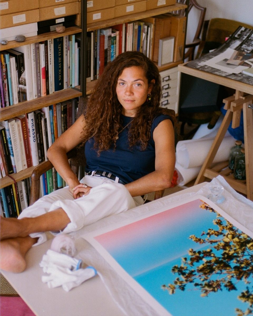 Photographer Lily Bertrand-Webb sitting at her desk with her feet up next to a photographic print.