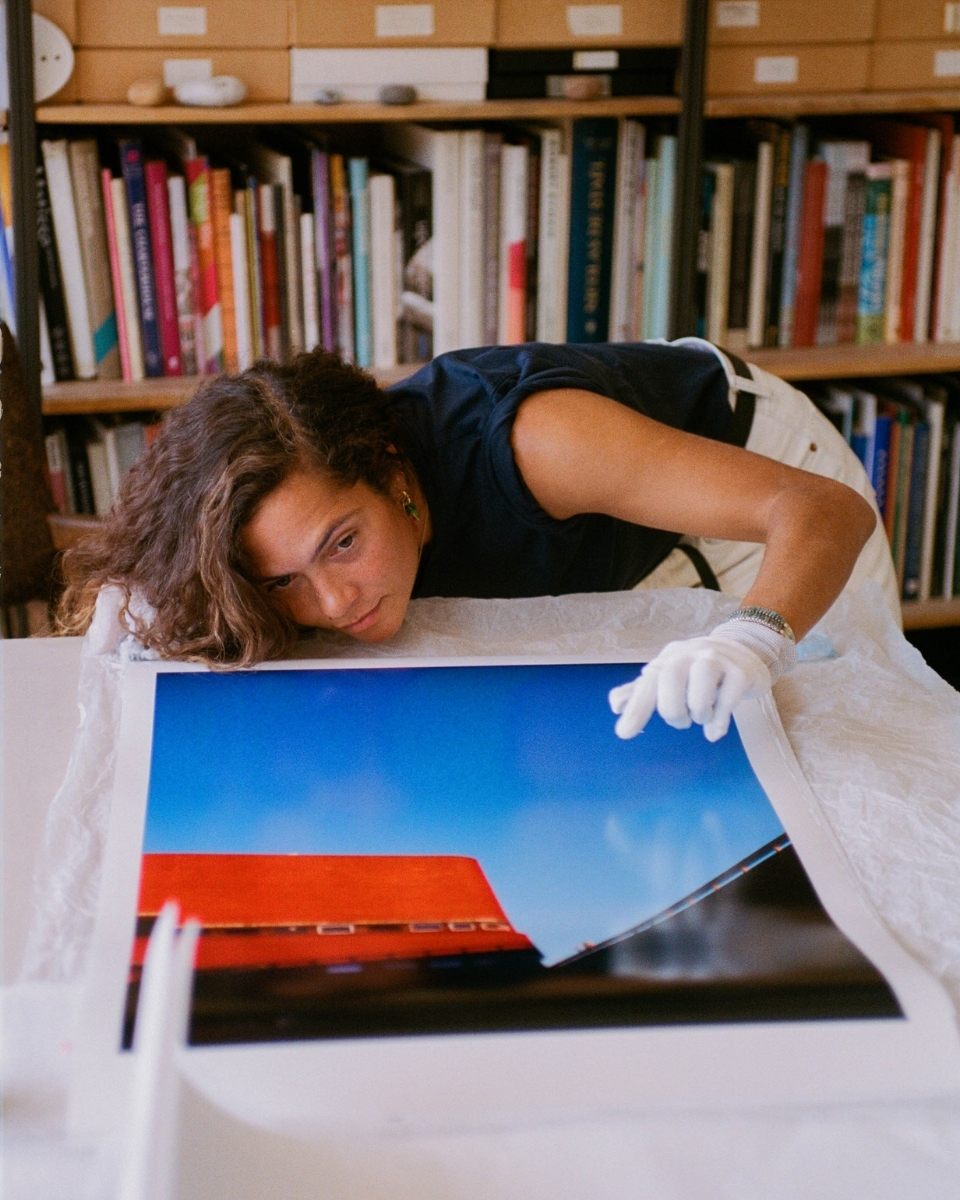 Lily Bertrand-Webb inspecting a new print at table level in her studio, ensuring the archival quality of her film-based photography.