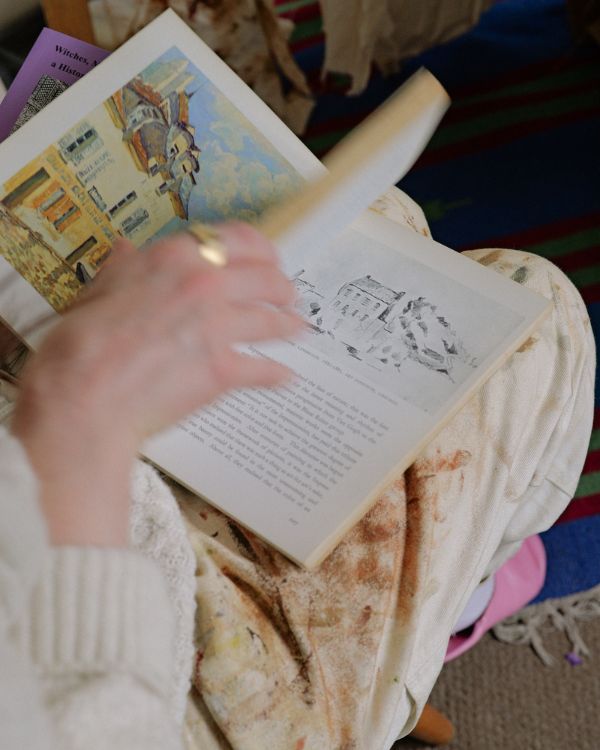 A small thumbnail preview showing artist Lily Rose Fine flicking through an art book in her studio for the Partnership Editions journal footer icon.