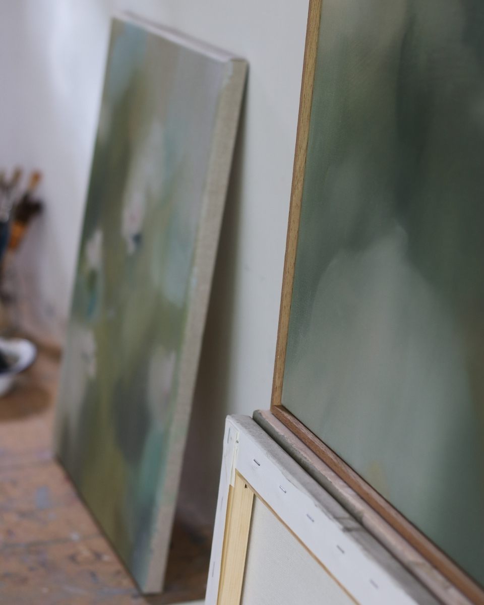 Framed and unframed abstract canvases leaning against a studio wall, showcasing Lisa Hardy’s organic colour pairings and textures.