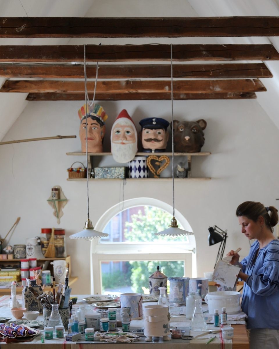 Artist Lisa Sandner in her studio, focused on painting an organic ceramic form amongst a series of works in progress.