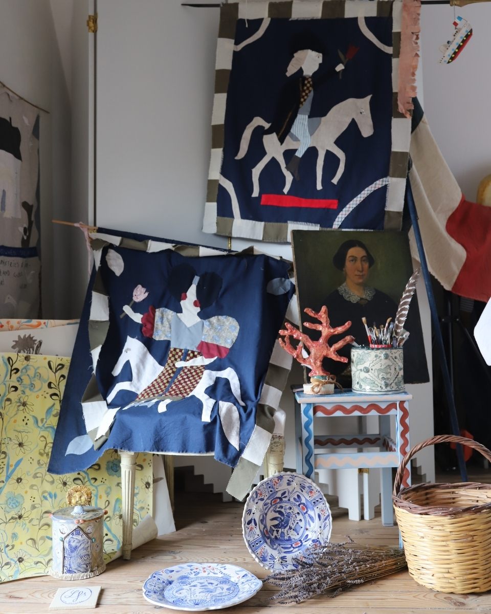 Lisa Sandner's studio interior showcasing decorative plates, a woven basket, and horse design quilts.
