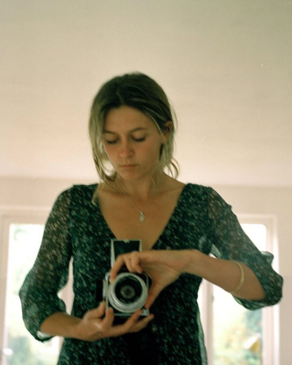An analogue self-portrait of photographer Lottie Hampson holding a vintage medium-format camera in her studio