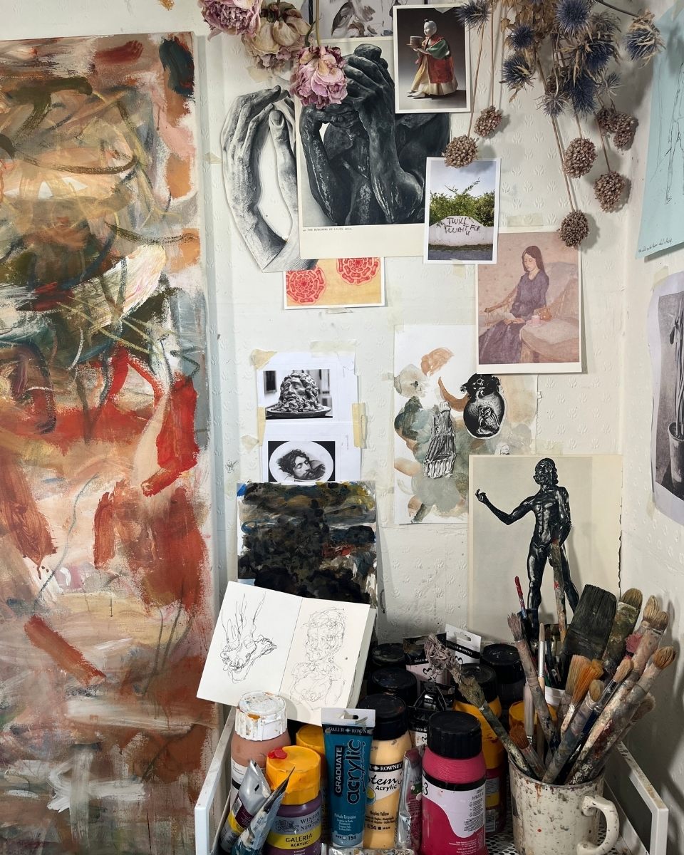 Maarten van den Bos’ studio wall featuring a curated mix of historical inspiration imagery, professional paintbrushes, and acrylic paints.