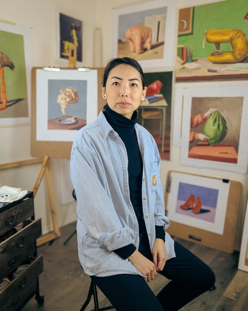 Artist Mamie Young sitting in her art studio in front of a series of finished oil paintings.