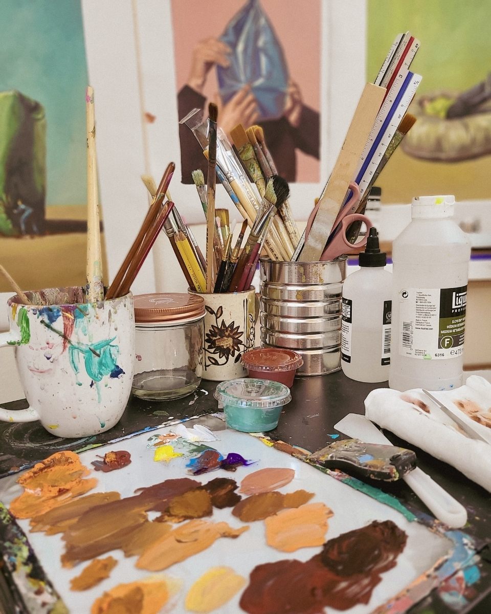 Close-up of artist tools and hand-mixed colour swatches in Mamie Young’s studio, highlighting her precise architectural approach to oil painting.