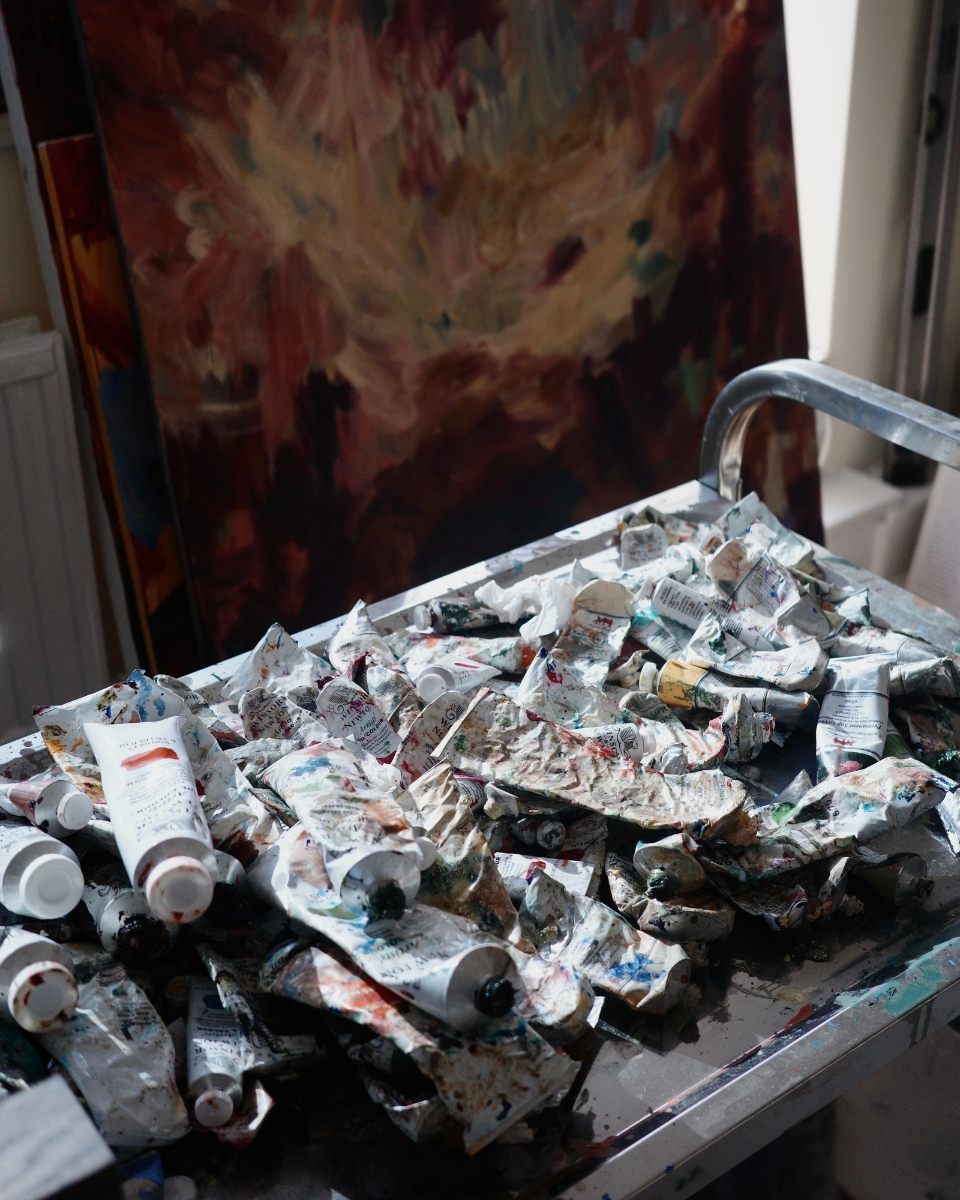 Detail shot of Mary West’s studio trolley, overflowing with a messy and vibrant arrangement of oil colors and pigments for her gestural works.