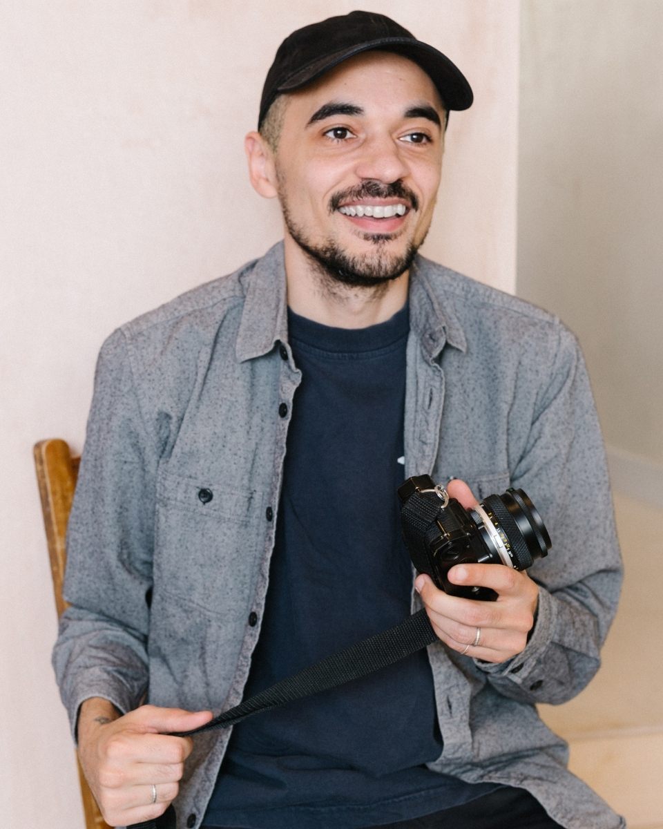 A portrait of photographer Matt Ritson holding a small film camera in his hand inside his studio.