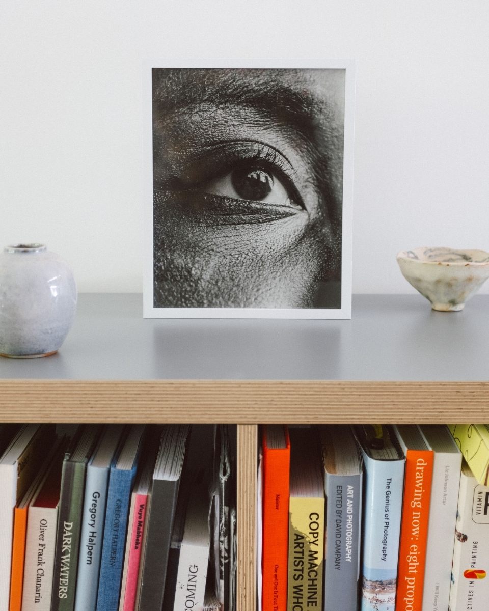 A styled, framed photographic print titled Eye by Matt Ritson displayed on a small bookshelf.