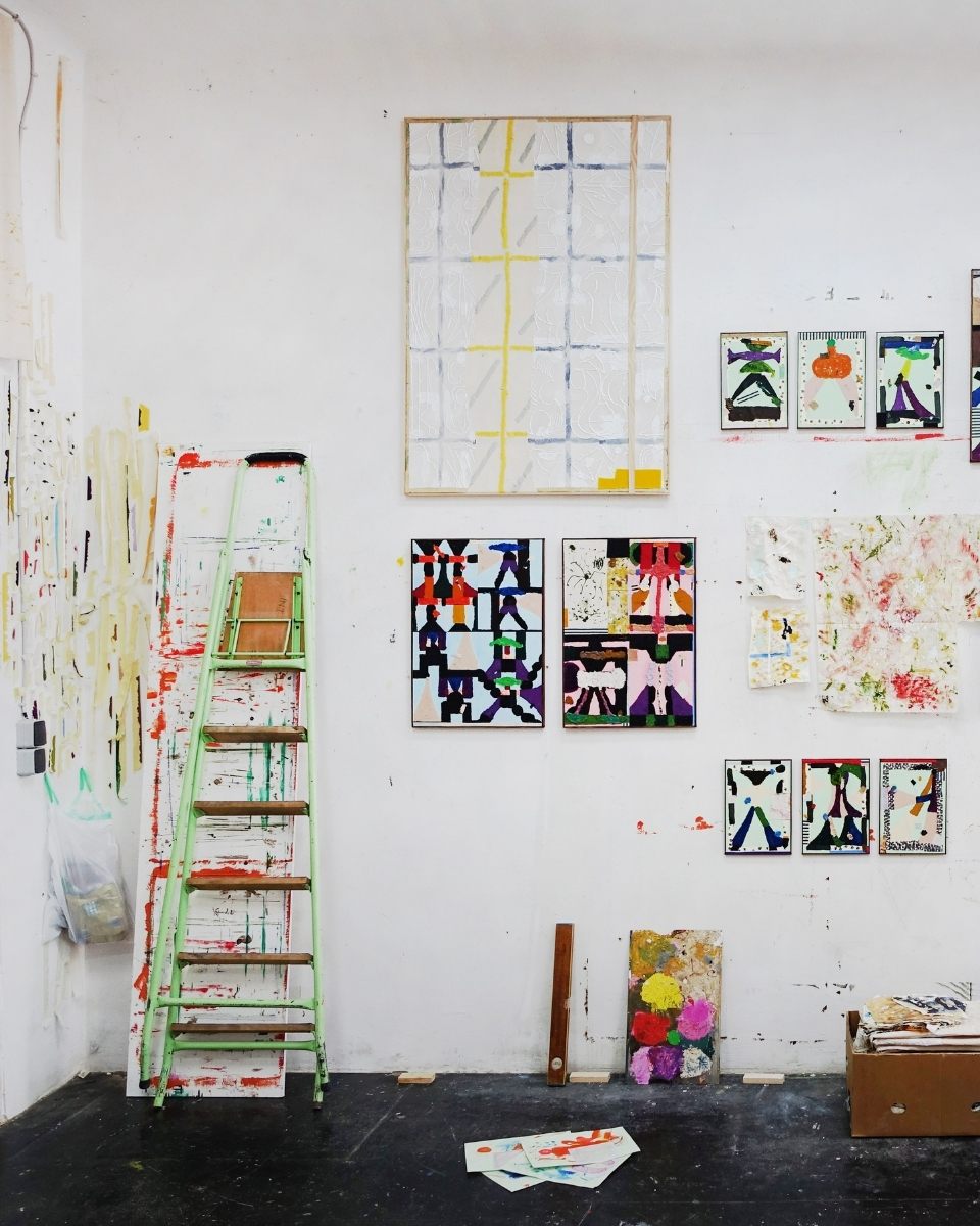 A corner view of Max Freund’s studio workspace, showcasing a mix of framed artworks, experimental drawings, and a green painter's ladder.