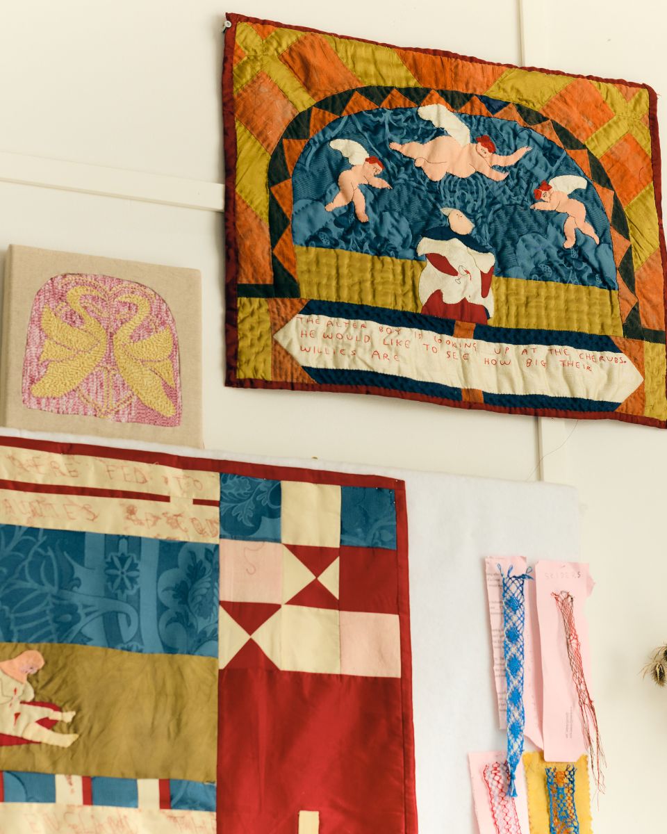 An artist studio wall filled with colourful hanging embroidery pieces and textile art by Molly Lester.