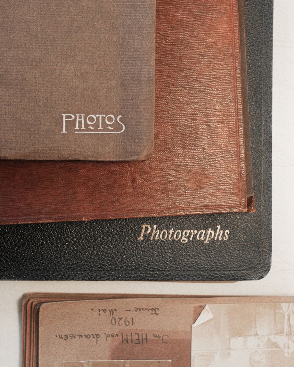 Top-down view of stacked vintage leather and cloth photograph albums with embossed lettering.