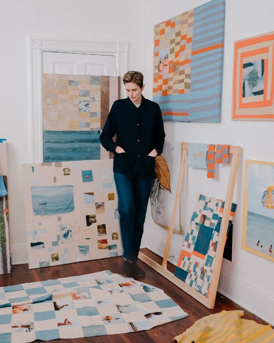 Full-length shot of artist Nathalie Basoski in her studio, surrounded by a curated collection of mounted and unmounted textile artworks.
