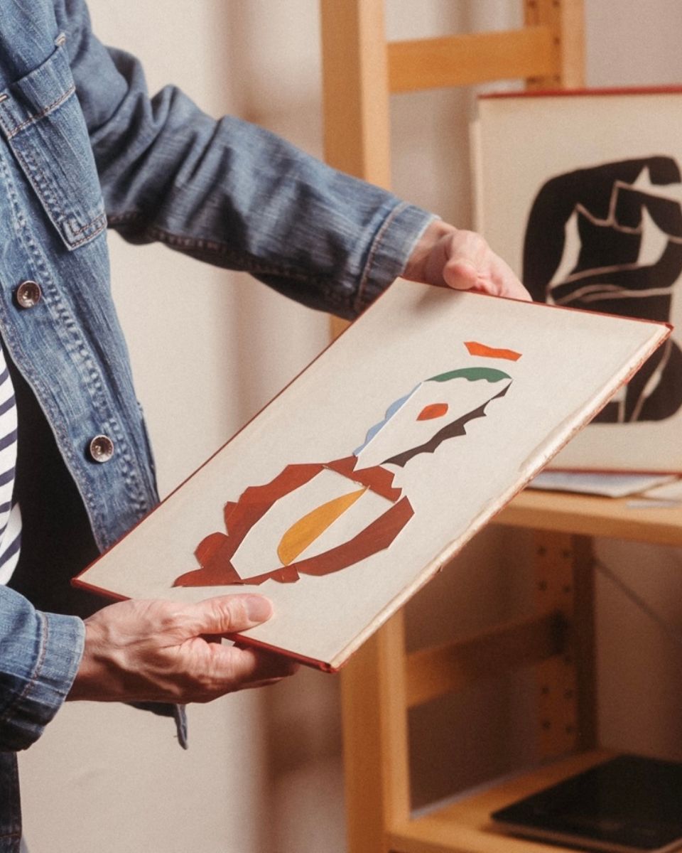 Artist Nathan Isaac holding small-scale geometric collage in his Newport studio, showcasing his signature use of bold color and balance.