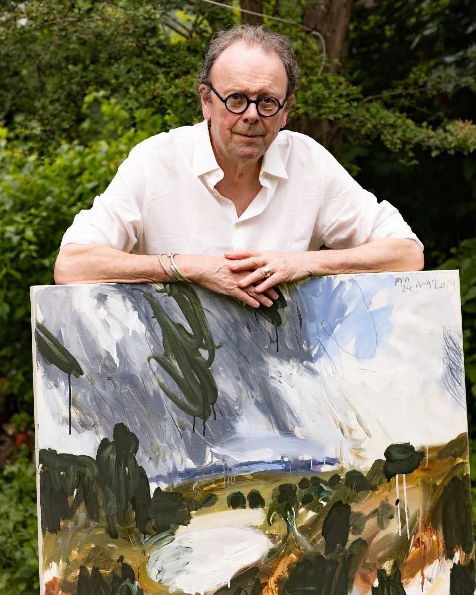 Artist Philip Maltman standing in his garden, holding a large-scale expressive oil painting.