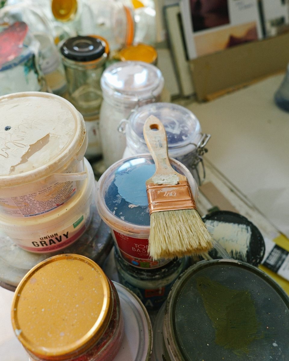 A detail shot of heavy paint tubs and used brushes in artist Philip Maltman's studio.
