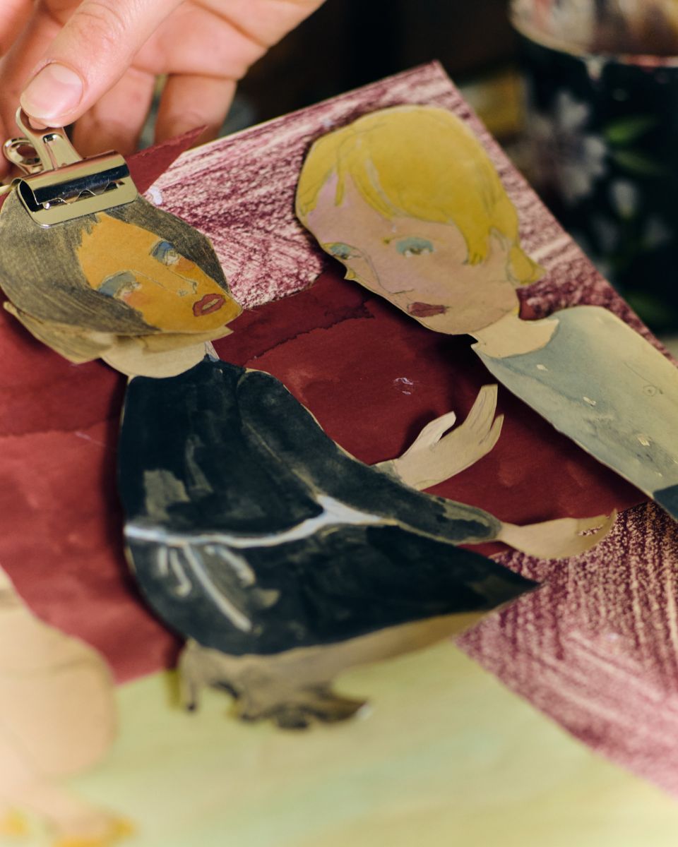 Close-up of a paper figurine collage clipped together inside Phoebe Howard's creative art studio.