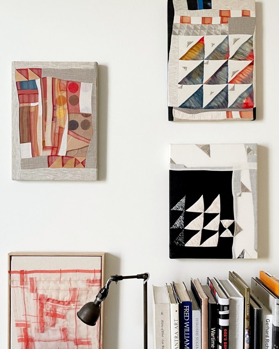 Small-scale geometric textile pieces by Phong Chi Lai styled on a home studio wall over a small bookshelf.