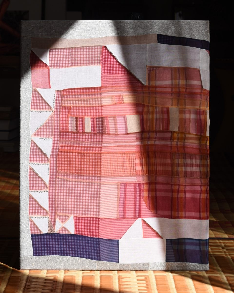Close-up of Phong Chi Lai's colourful geometric textile quilt artwork illuminated by warm natural lighting.