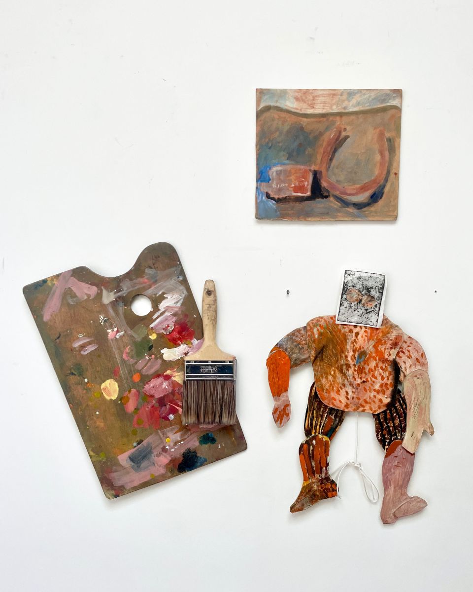 Detail of Rebecca Ashton’s studio wall, featuring a hand-made figurine, a used palette, and an original oil painting.