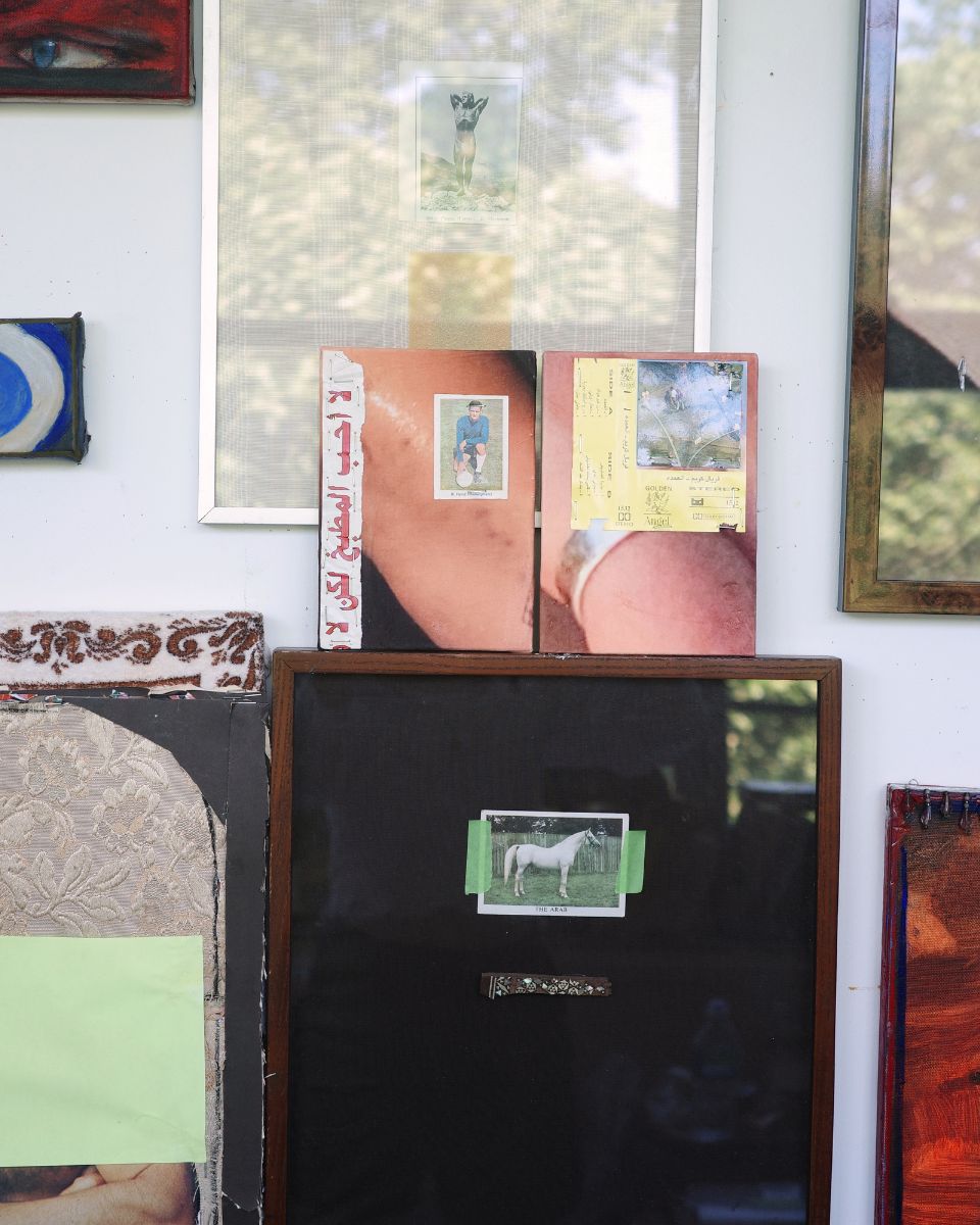 Detail of small unframed mixed-media art pieces resting on top of a larger framed painting in the studio.