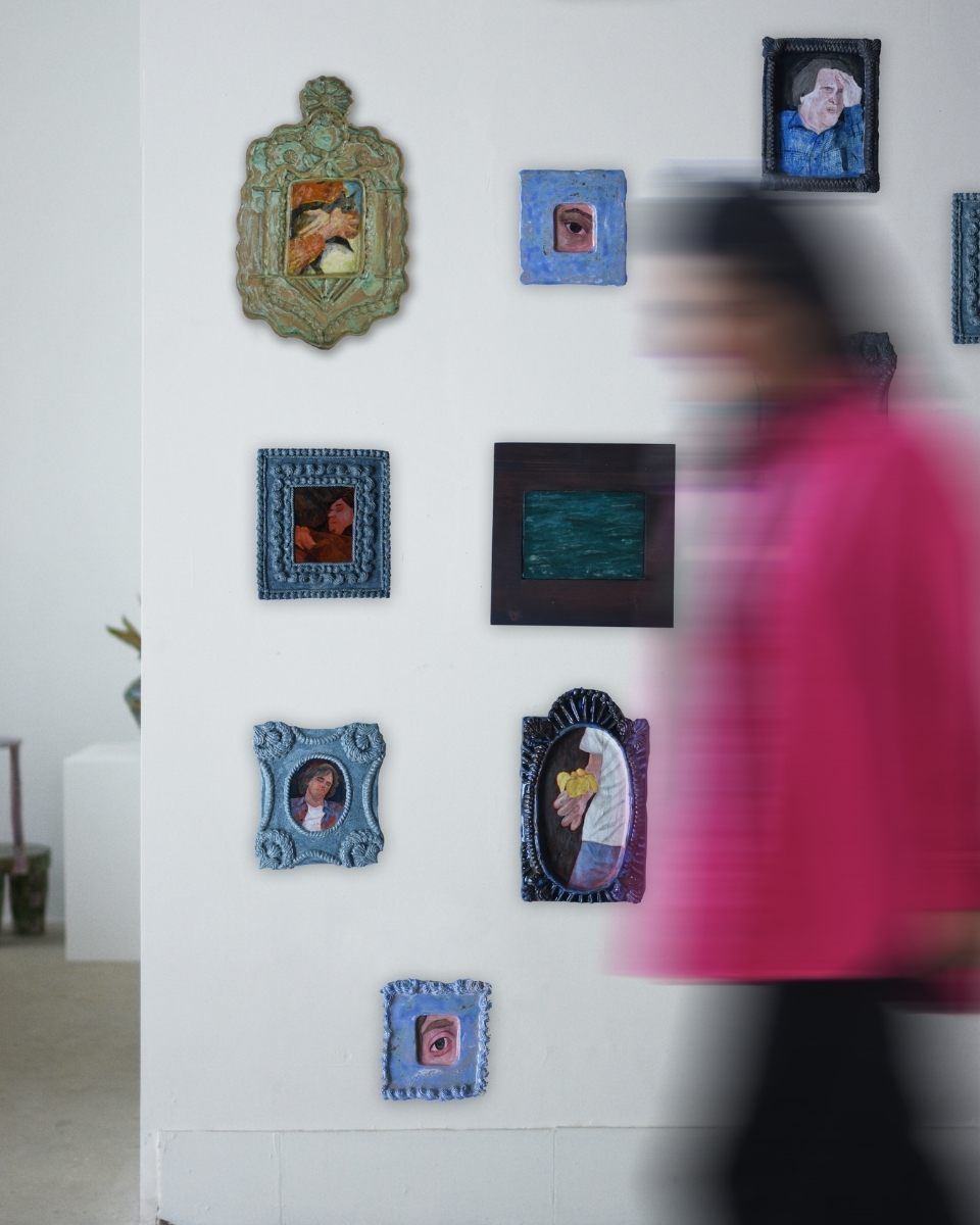 A dynamic, prolonged shutter speed photograph capturing artist Samantha Kerdine walking past her studio wall adorned with her final framed paintings