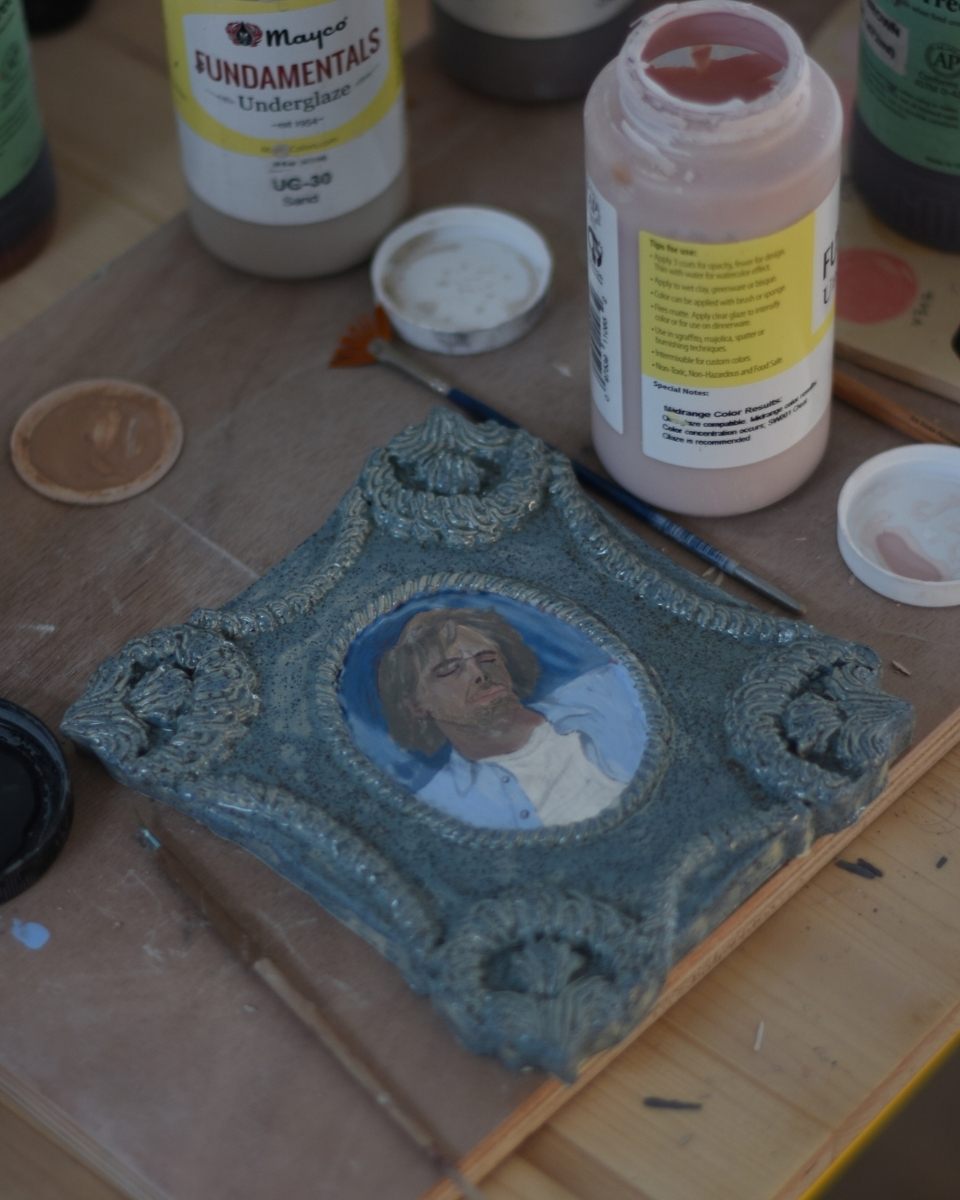 Close-up of Samantha Kerdine’s painting process, showing a small-scale artwork in progress next to vibrant underglaze ceramic paints.