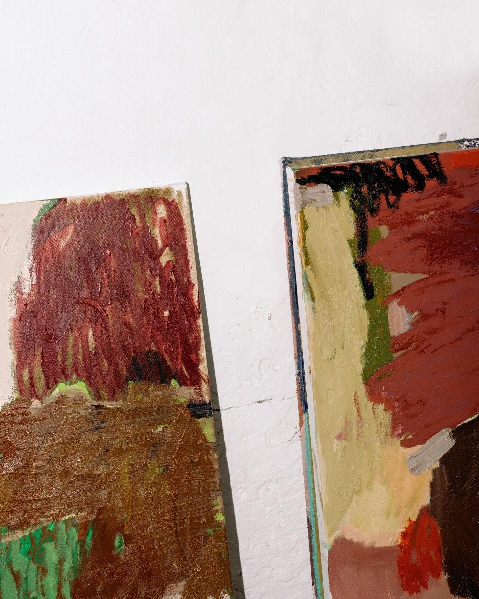 A high-detail flash photograph capturing the textured corners of two Sara Winfield paintings.