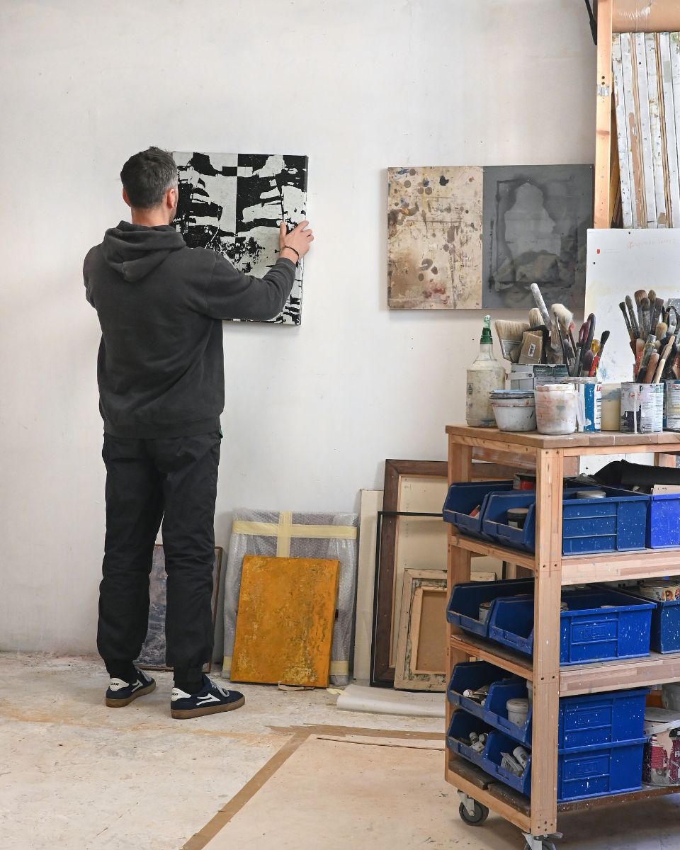 Simon Job adjusting a landscape painting on the wall for the Process Online Exhibition at Partnership Editions.