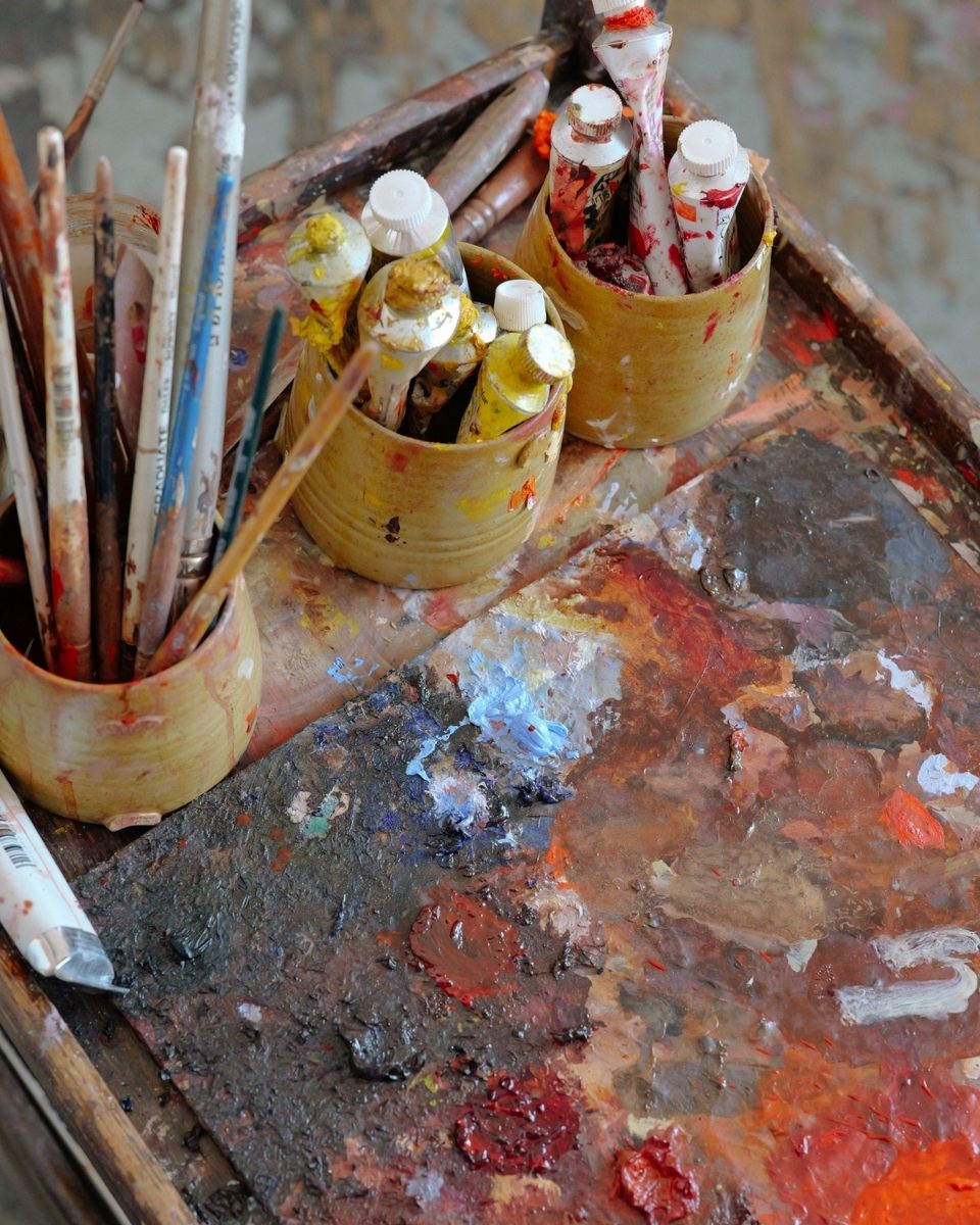 Detail shot of Sophie Glover’s vibrant paint palette and tubes on her wooden trolley.