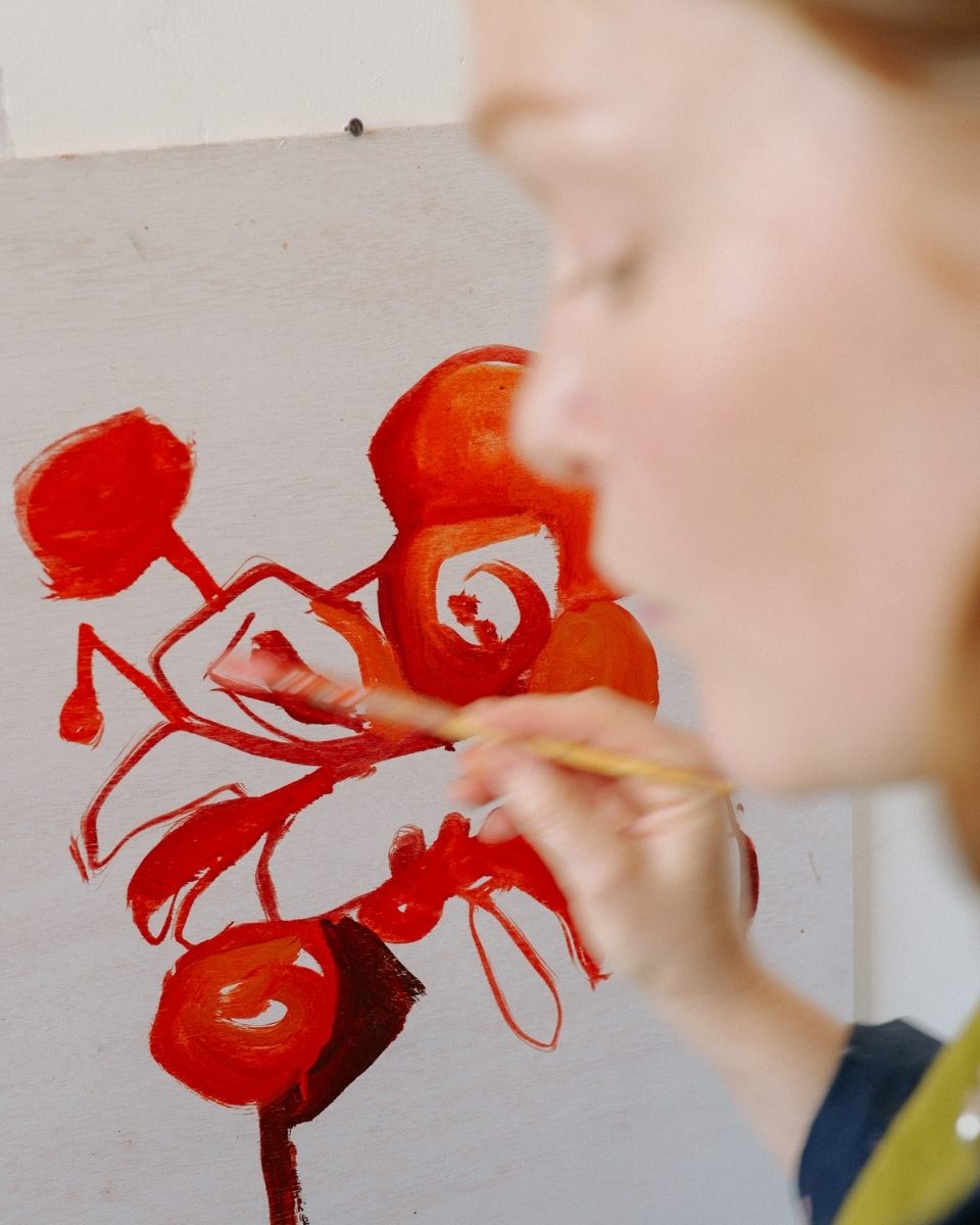 A close-up motion-blur photograph of Sophie Glover in front of a small-scale work-in-progress, capturing the energy of her creative flow.