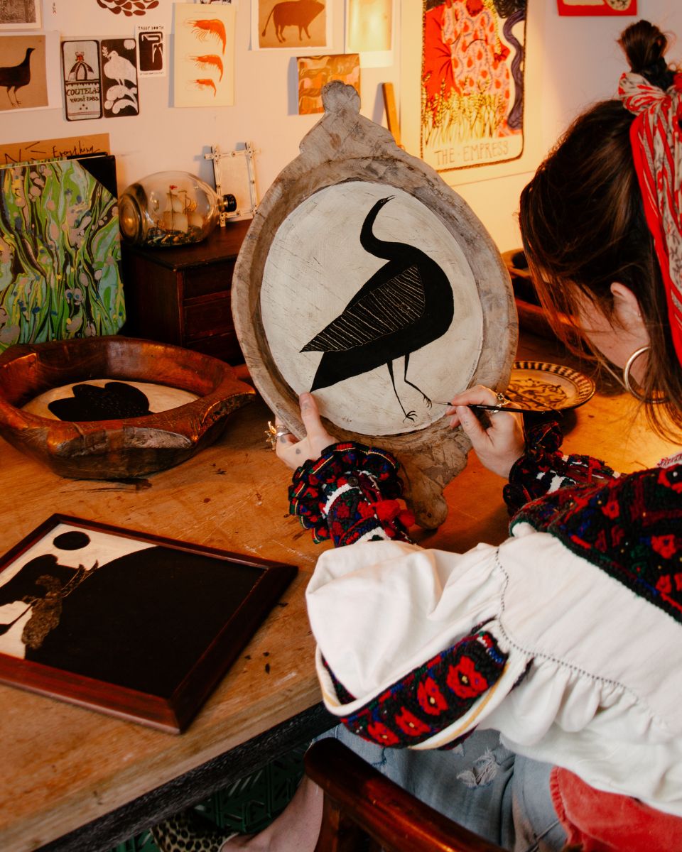 Artist Tabby Booth working on a bird motif painting in her studio for the Mandy Hudson and Tabby Booth Artist Drop at Partnership Editions.