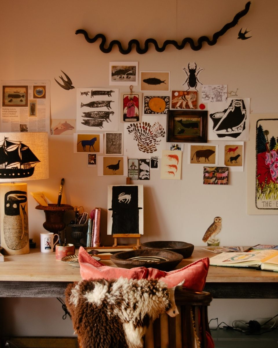 A vibrant detail of Tabby Booth’s desk, featuring character drawings, a personalised hand-painted lamp, and an open sketchbook in her colourful studio.