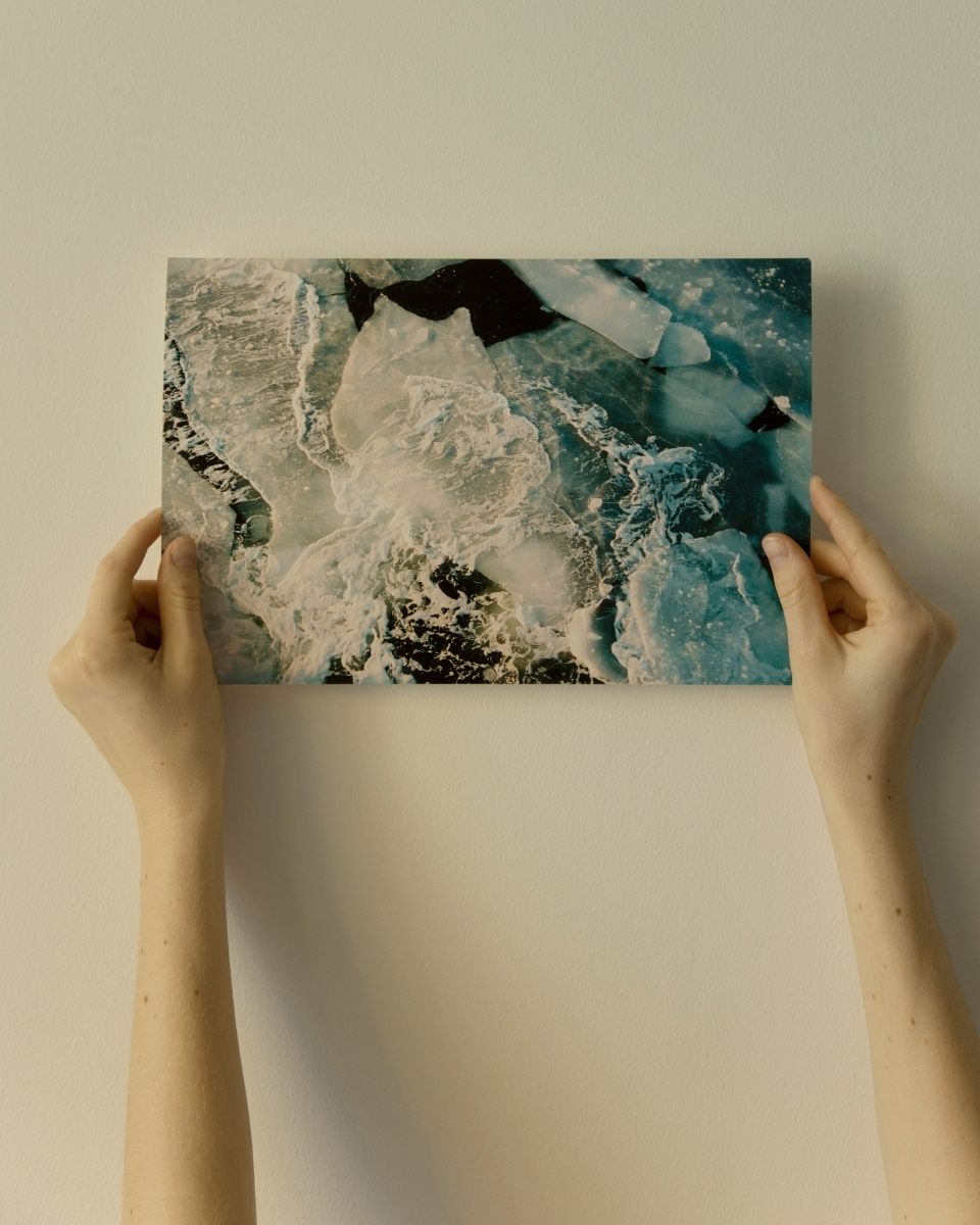 Thea Løvstad’s hand holding a high-contrast photographic print of icy water.