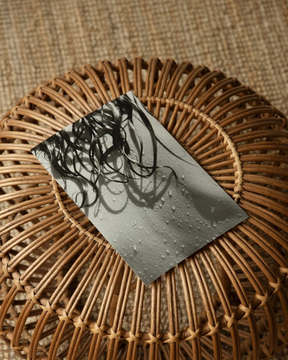 A black and white photography print of a wet hair detail by Thea Løvstad, displayed on a minimalist stool in her studio.