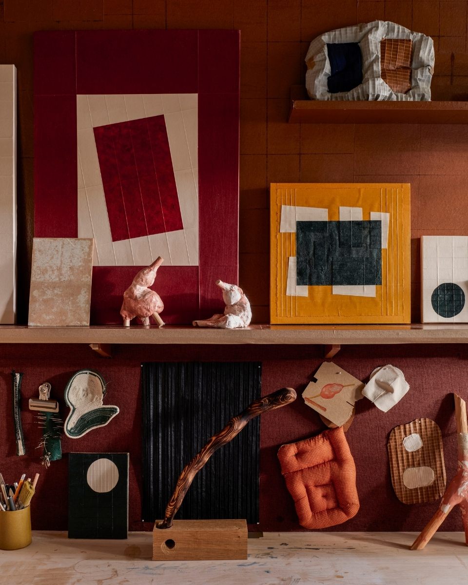 Detail of Tom Collison’s vibrant studio desk, featuring colourful hand-painted figurines and paper maquettes used for spatial study.